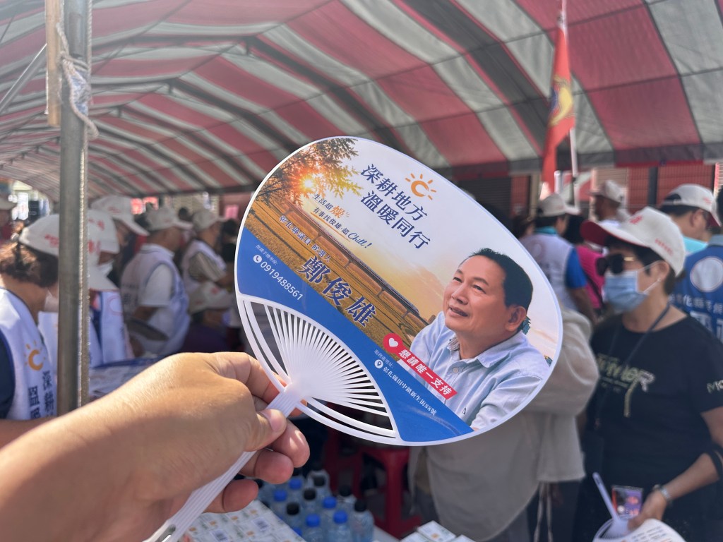 台灣選舉文宣小物手拿印有候選人照片與深耕地方標語的塑膠扇子