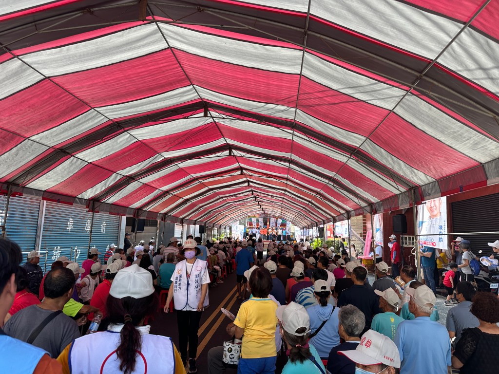 台灣選舉造勢大會紅白相間帆布棚架下座無虛席的基層民眾與支持者